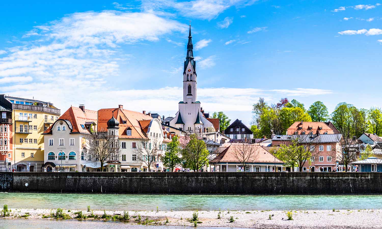 Europäische Stadt mit Fluss, Kirche und alten Gebäuden bei blauem Himmel.