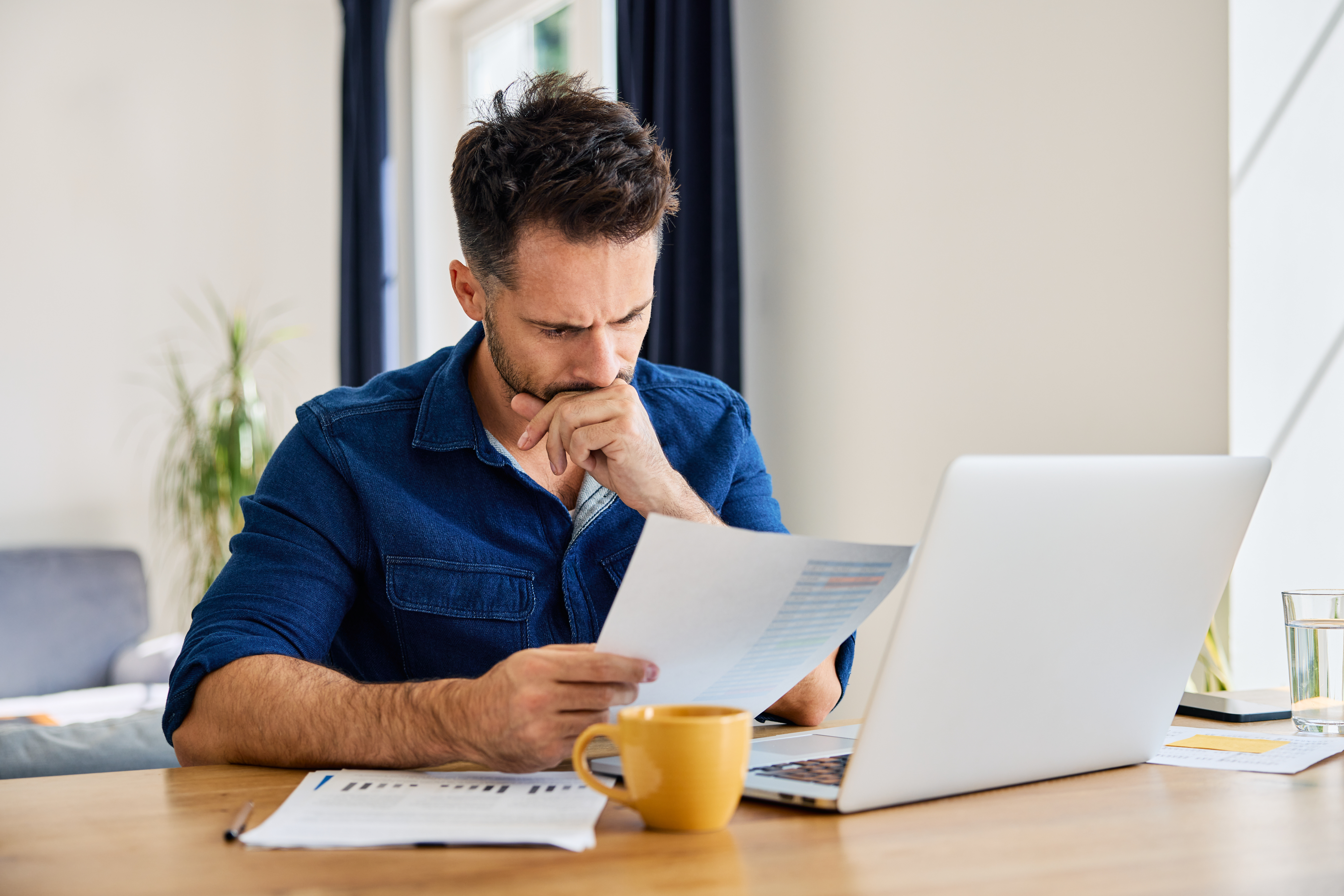 Trauriger Mann schaut sich zu Hause Finanzunterlagen an