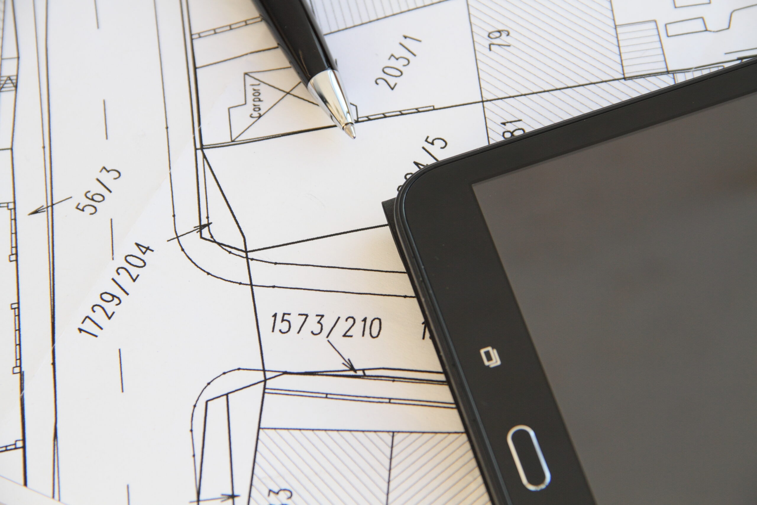Tablet mit Kugelschreiber und Vermessungsplan