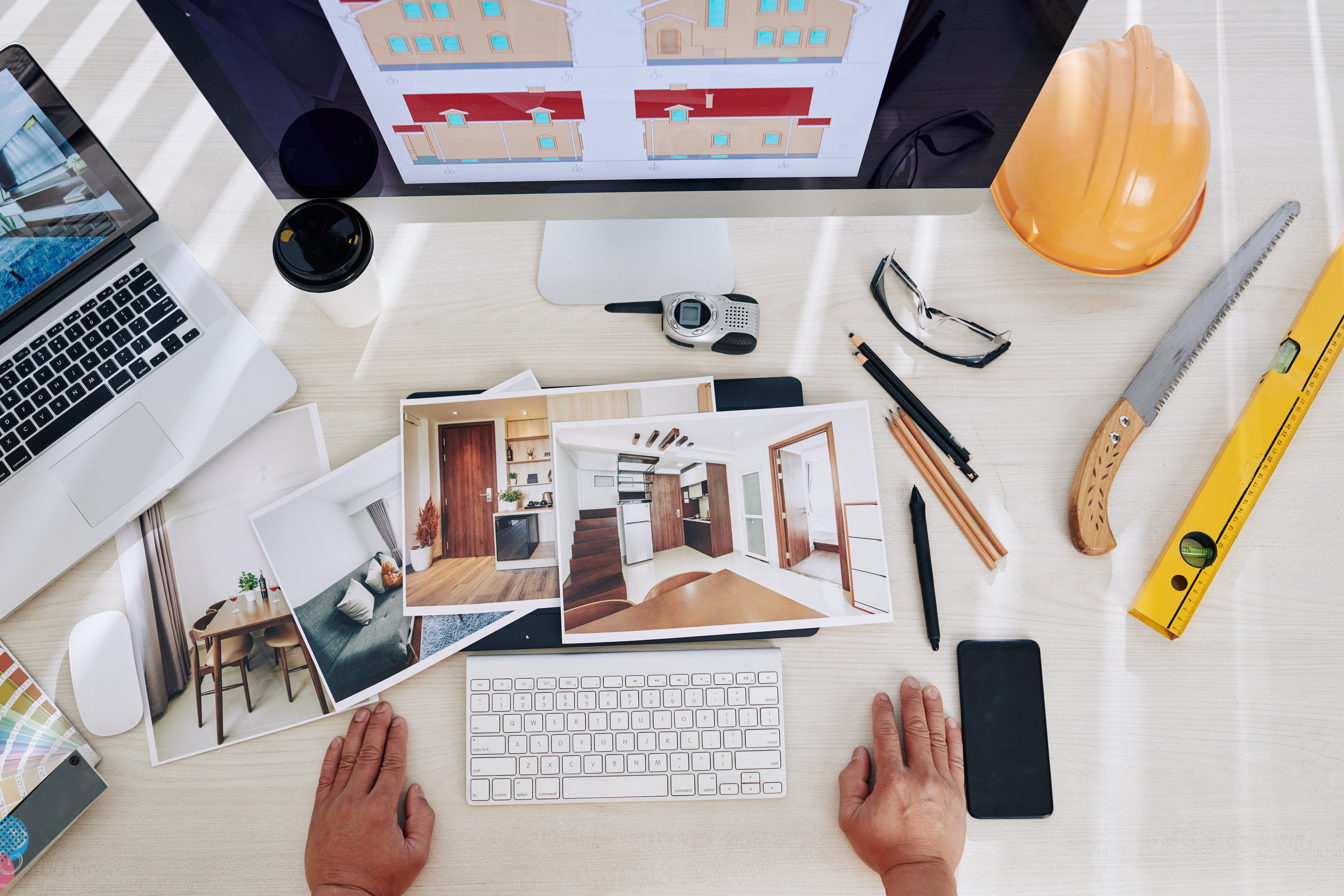 Eine Person sitzt an einem Schreibtisch, vor ihr ein Bildschirm mit Aufnahmen einer Immobilie