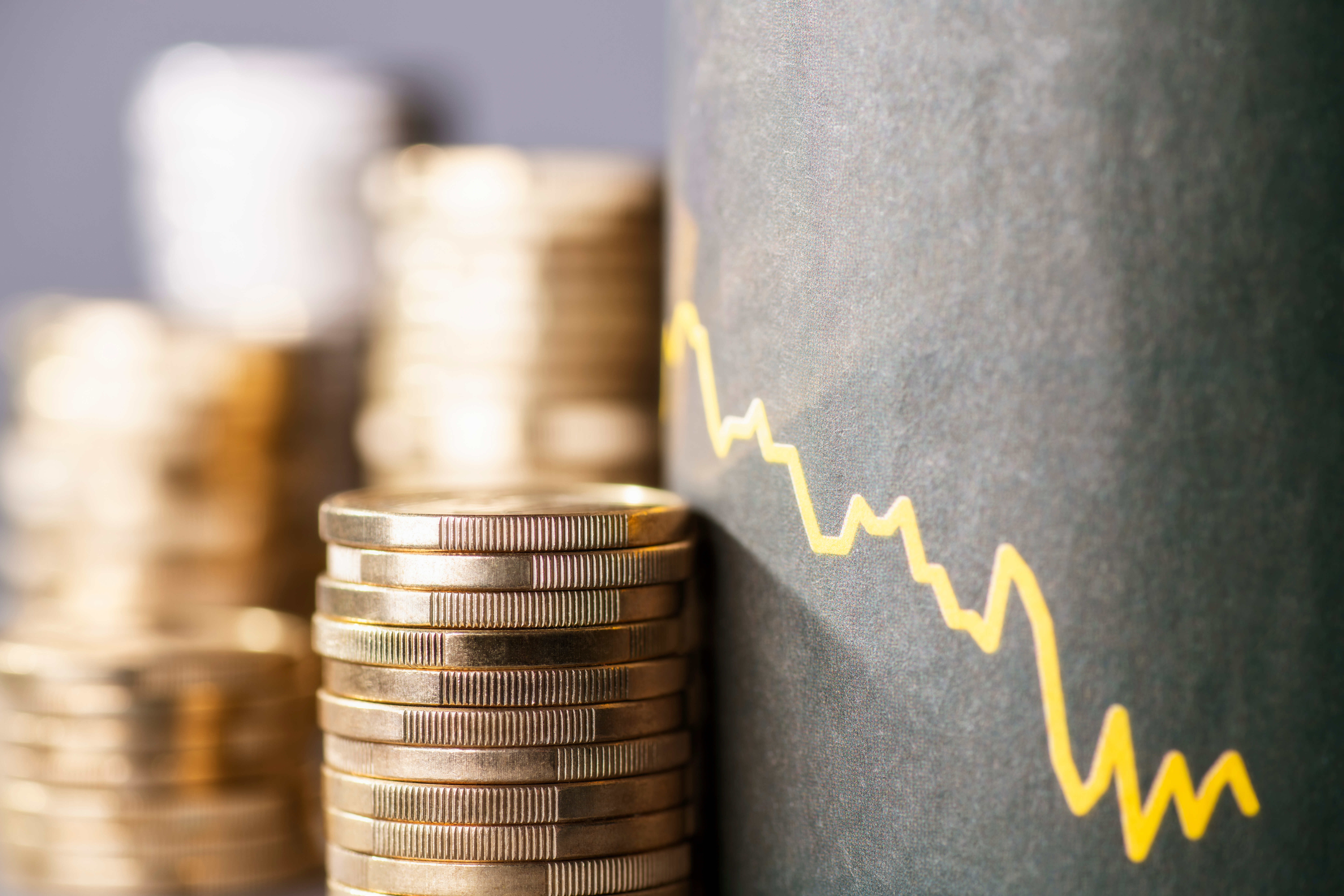 Münzstapel neben einer fallenden Statistik-Kurve