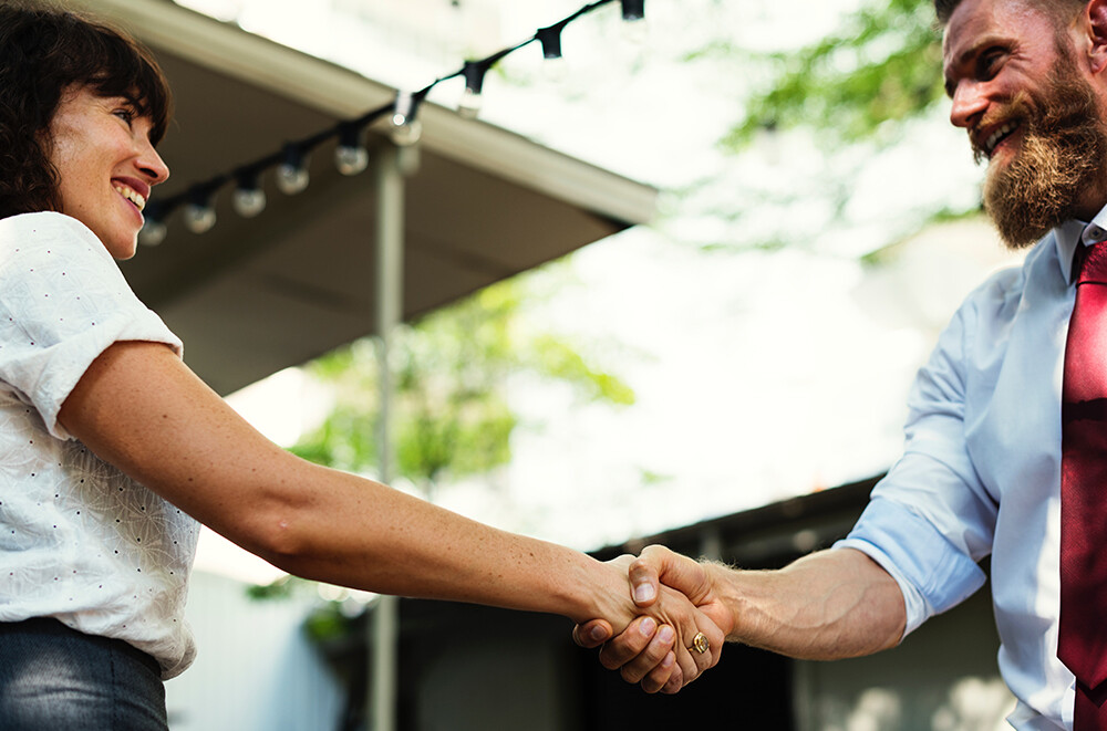 Ein Immobilienmakler schüttelt einer Kundin die Hand