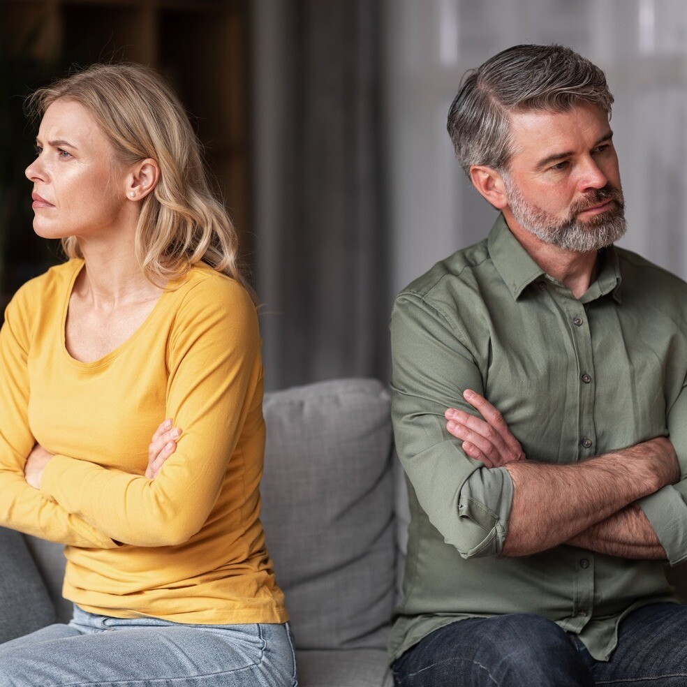 Mann und Frau sitzen voneinander abgewandt: Immobilie im Trennungsfall