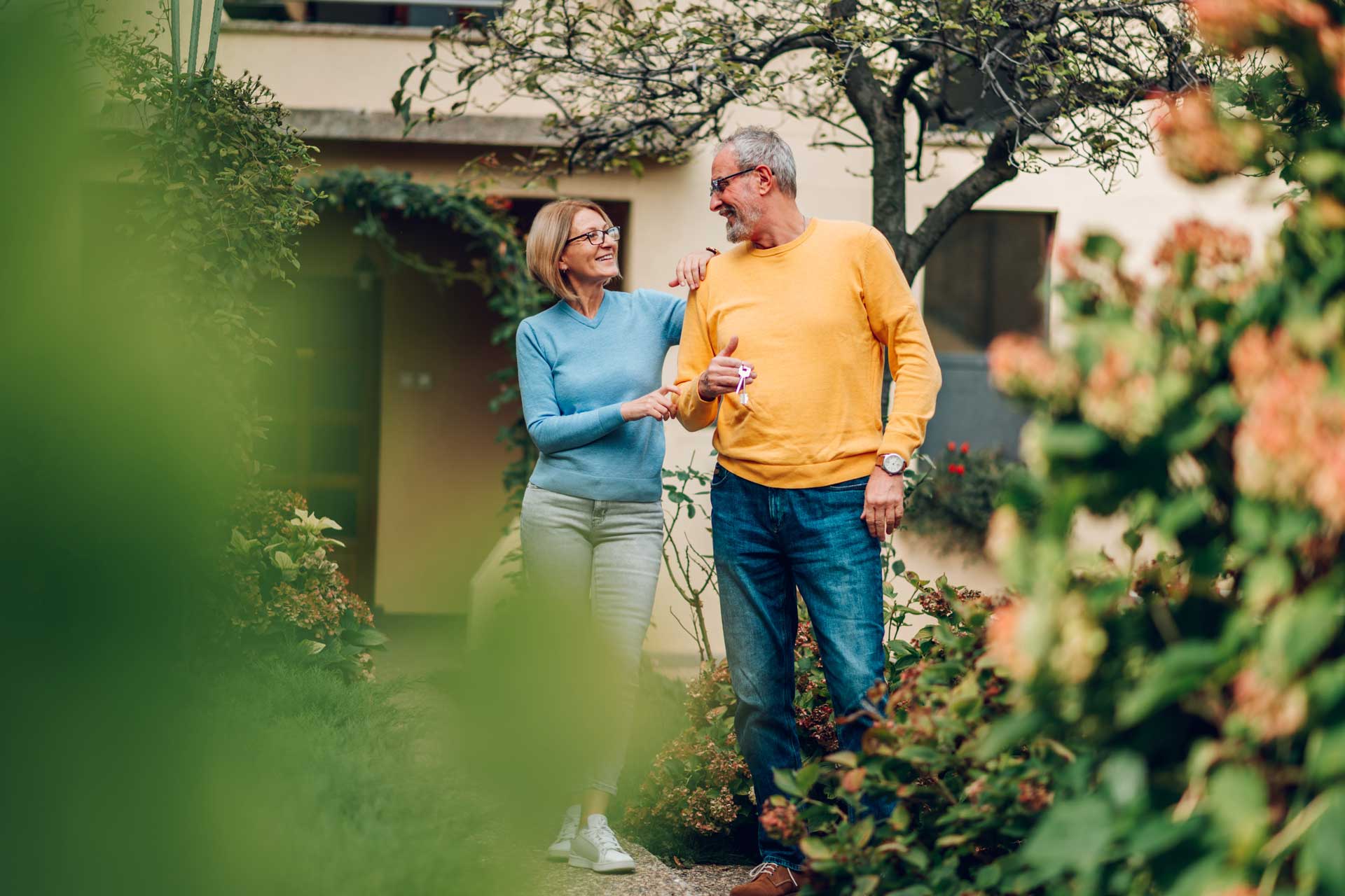 Mittelaltes Paar hält Schlüssel zu neuem altersgerechten Haus in der Hand