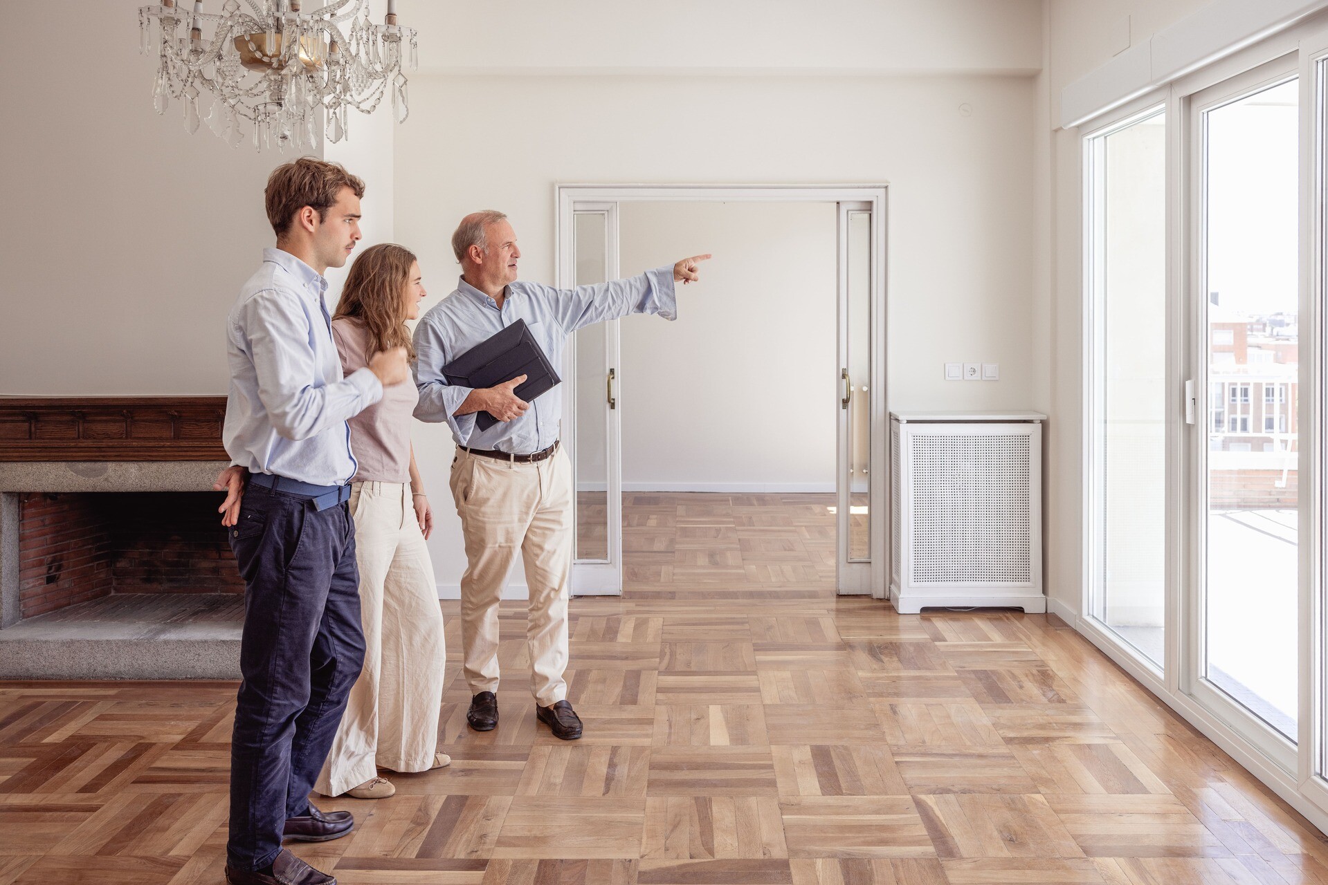 Ein Immobilienmakler zeigt einem jungen Paar eine leerstehende Luxuswohnung