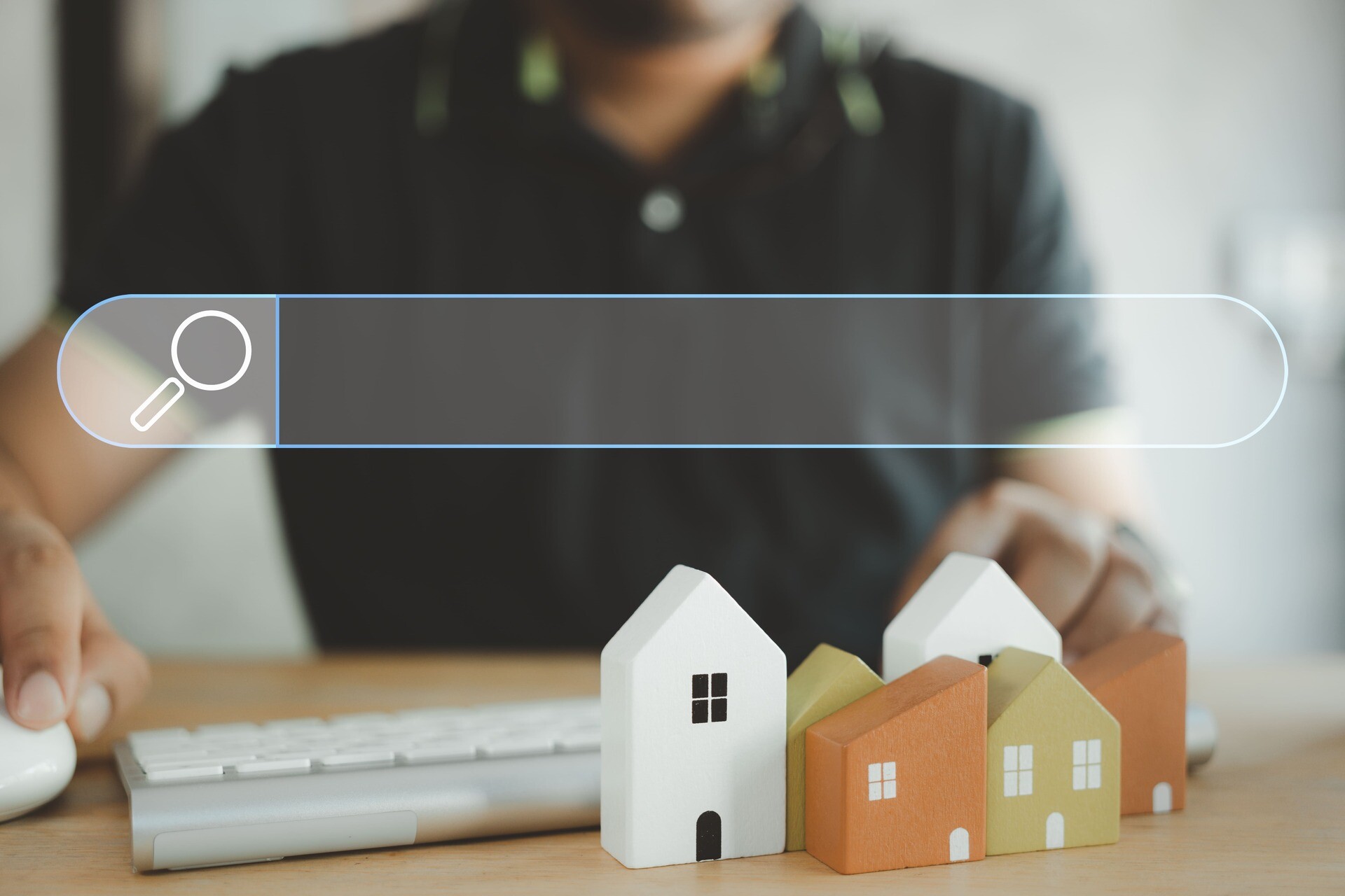 Wohnungssuche und Big-Data-Konzepte im Zusammenhang mit Suchmaschinenoptimierung; eine männliche Hand bedient Maus und Tastatur in einer Café-Bar, über der ein Suchmaschinen-Symbol