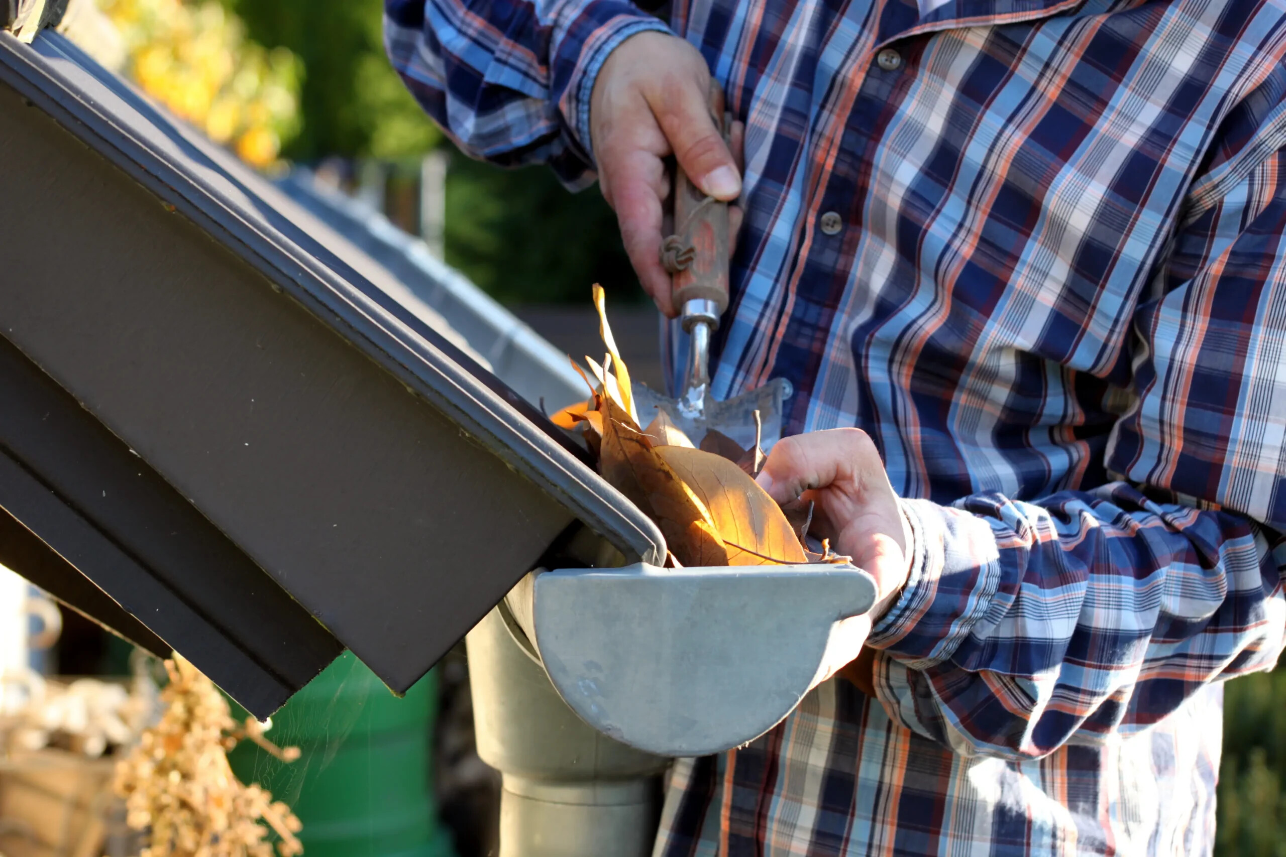Person reinige Regenrinne