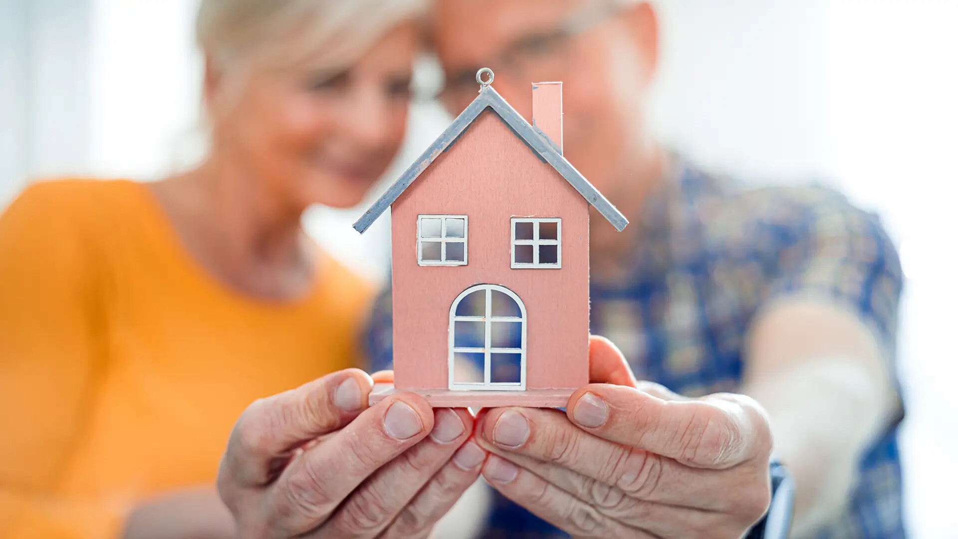 Seniorenpaar mit Modellhaus