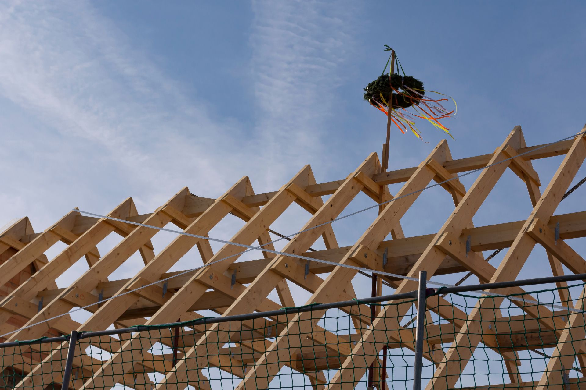 Holzdachbau mit Kranz vor blauem Himmel.
