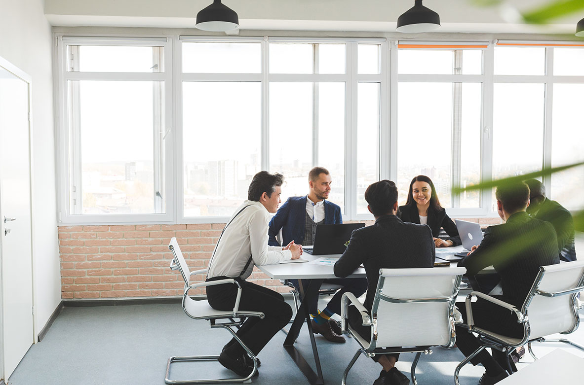 Mehrere Leute treffen sich zu einer Versammlung, einem Meeting und besprechen sich in einem Büroraum