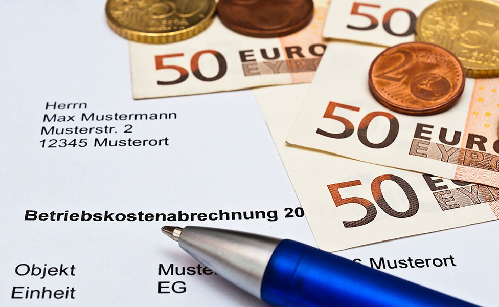 Muster-Betriebskostenabrechnung mit einem Stift und Geldscheinen