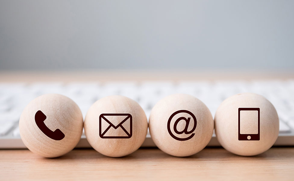 Holzkugeln mit Icons für Telefon, Brief, E-Mail und Smartphone als Kommunikationsmittel im FAGG