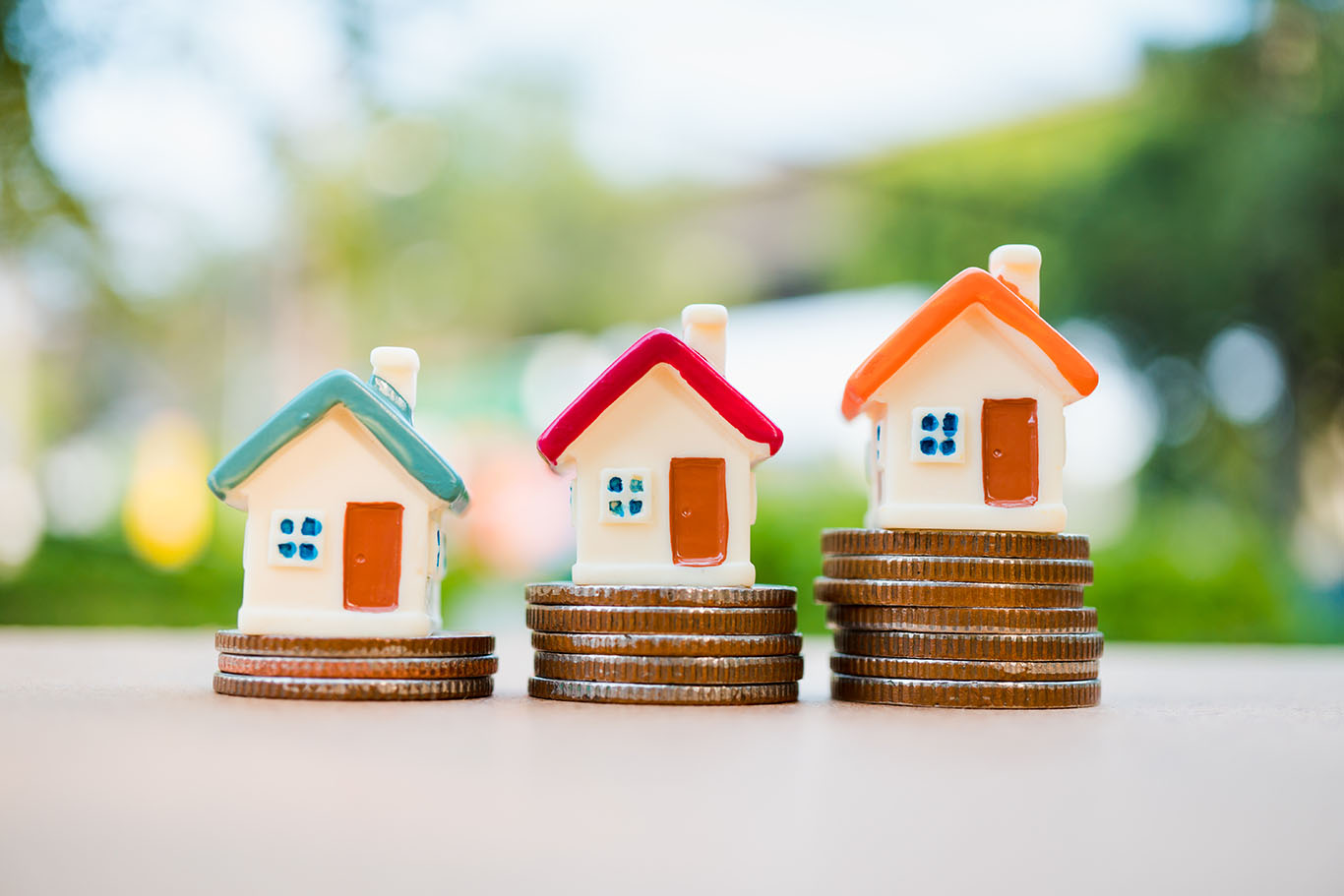 3 kleine Häuser stehen aufsteigend auf Münzen