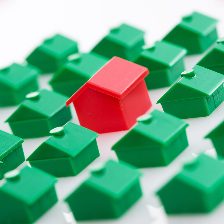 viele grüne und ein rotes Haus aus Monopoly