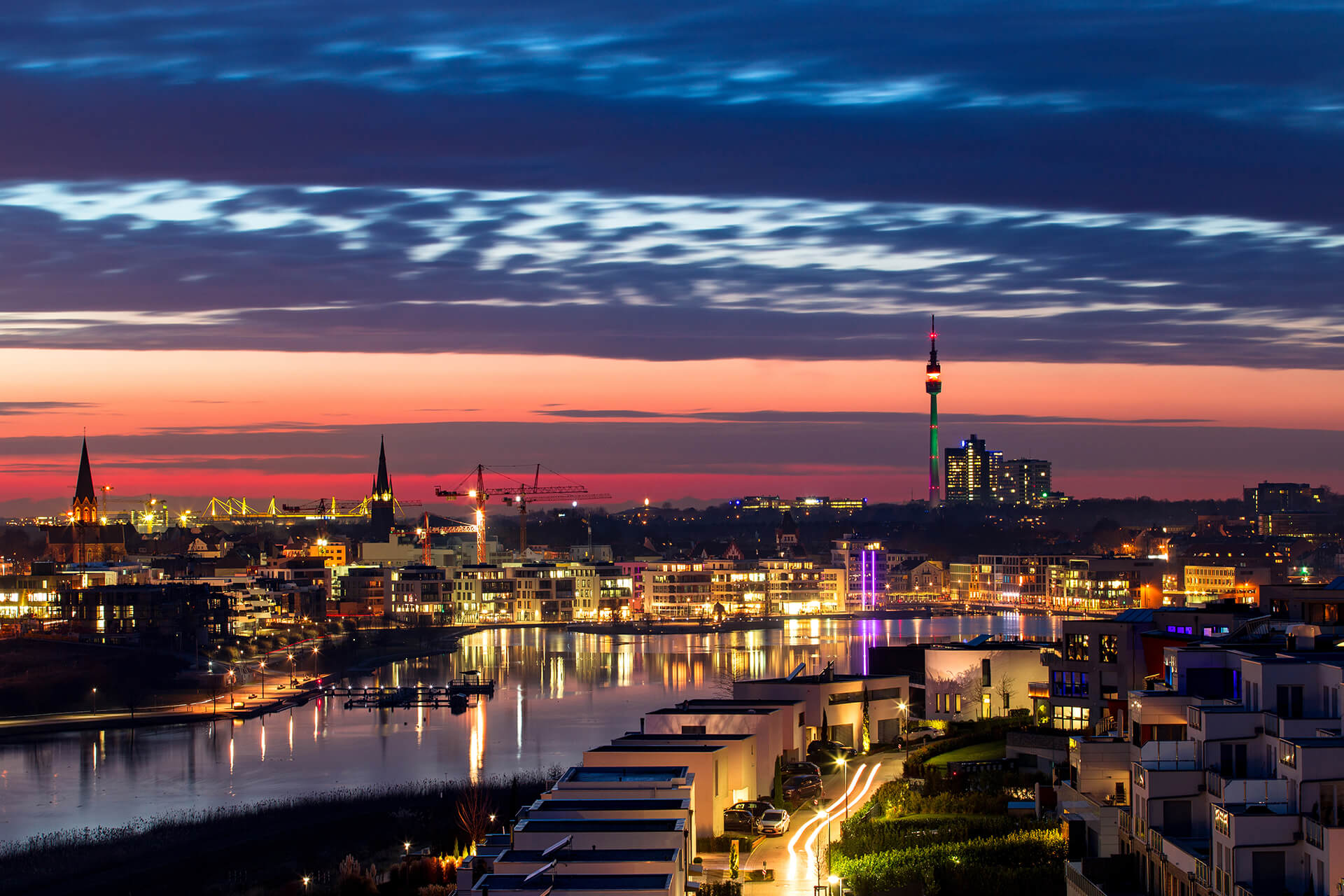 Die Lichter der Stadt spiegeln sich bei Nacht auf dem Wasser.