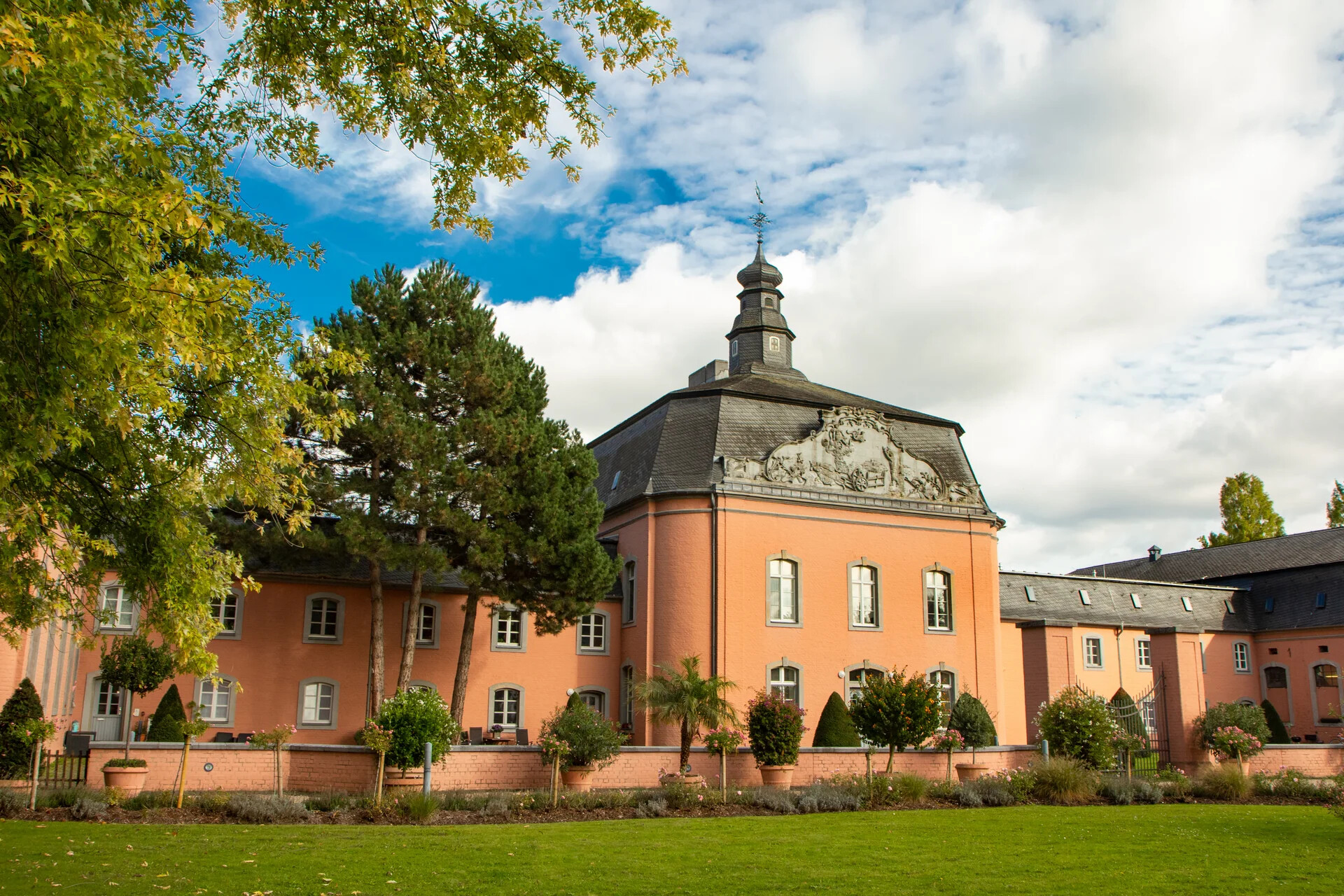 Pfirsichfarbenes historisches Gebäude mit Turm und kunstvollen Schnitzereien.