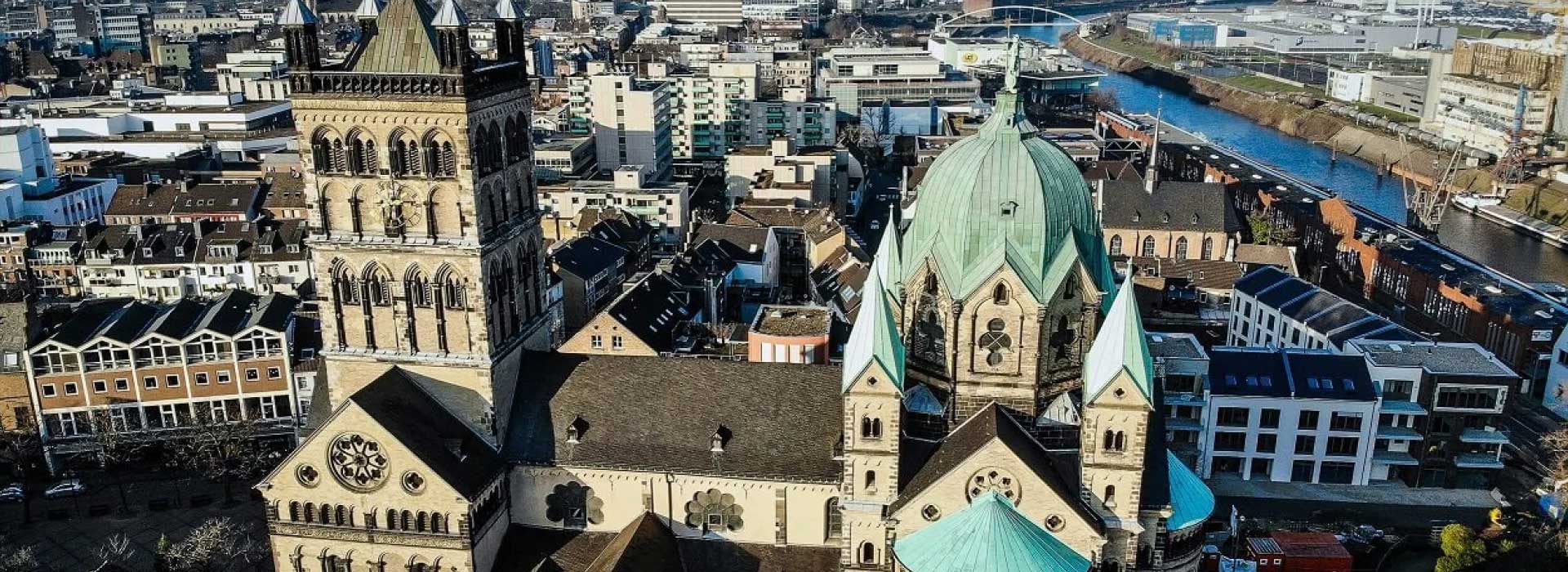 Historische Kirche mit grünen Kuppeln in Flussnähe, Stadtansicht.