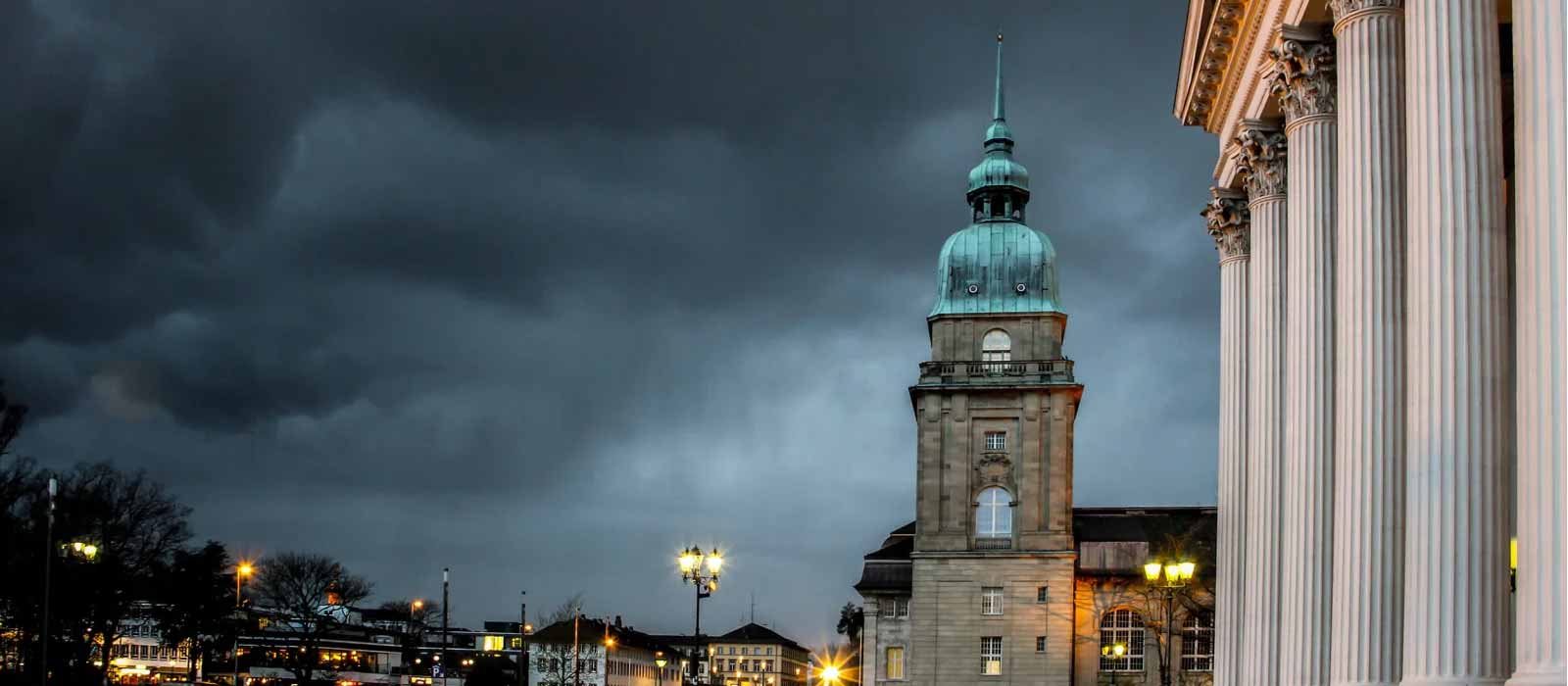 Historisches Gebäude mit grüner Kuppel vor dunklem Himmel.