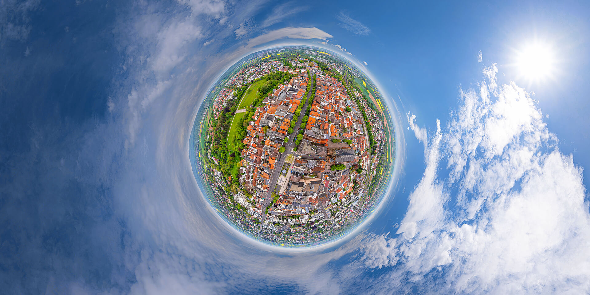 Kleine Planetenansicht einer Stadt mit blauem Himmel und Sonne.