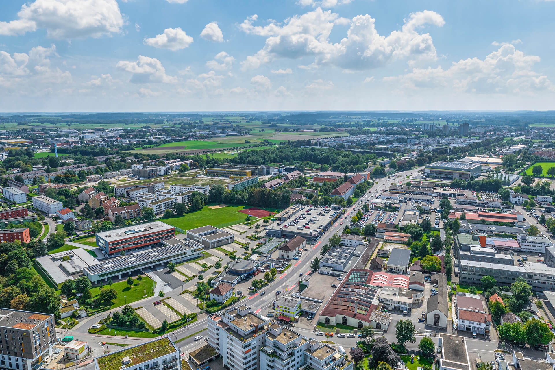 Vorstadt mit Gebäuden, Straßen, Feldern und Wolken.