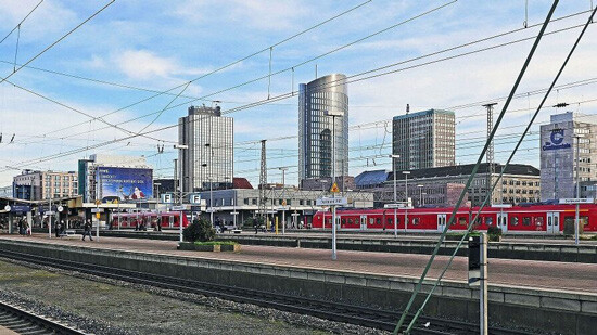 Stadtbahnhof mit roten Zügen, Menschen und modernen Gebäuden.