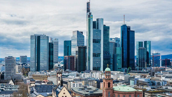 Hohe Wolkenkratzer ragen über alte Gebäude unter Wolken.