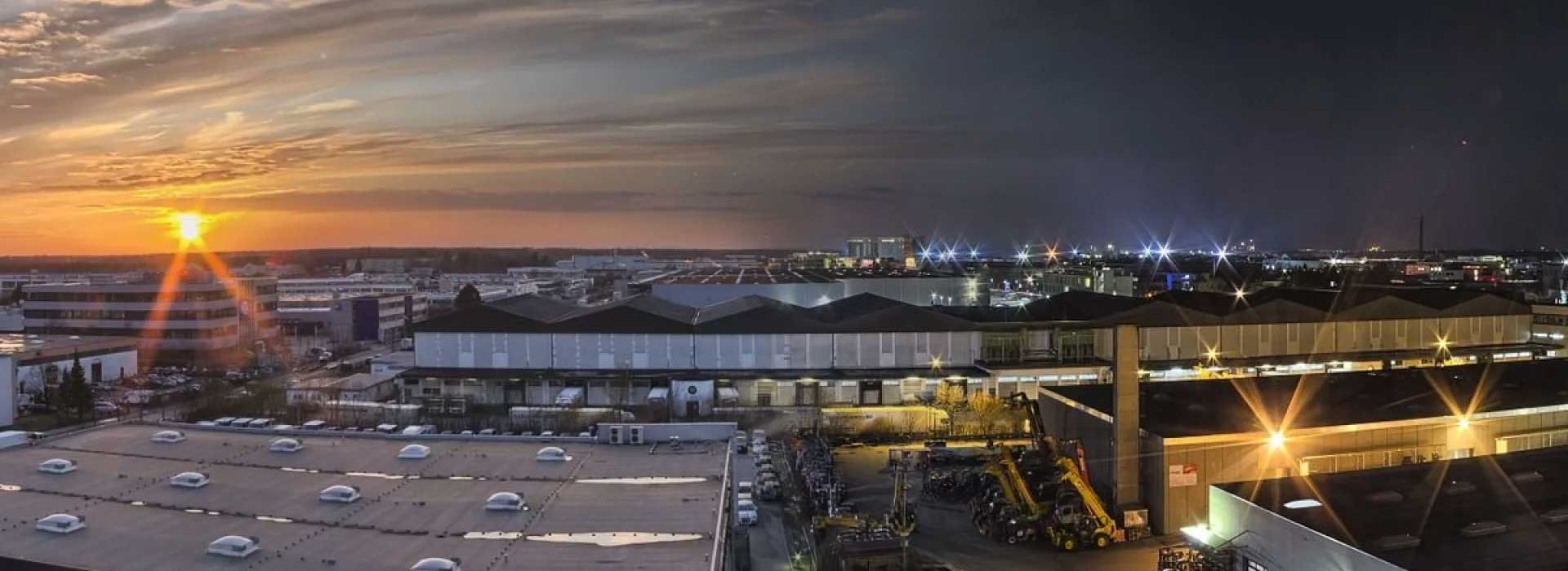 Industriegebiet bei Sonnenuntergang mit fernen Lichtern der Stadt.