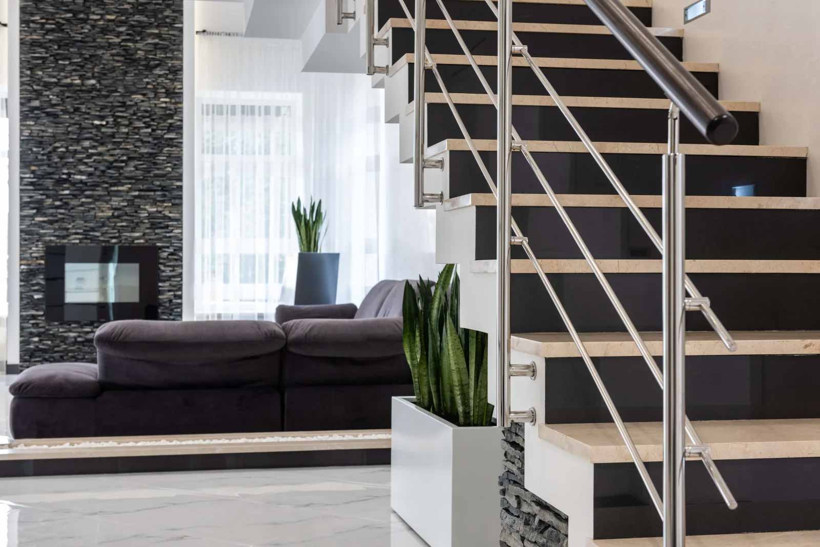 Modernes Wohnzimmer: schwarzes Sofa, Kamin, Treppe, Pflanzen.