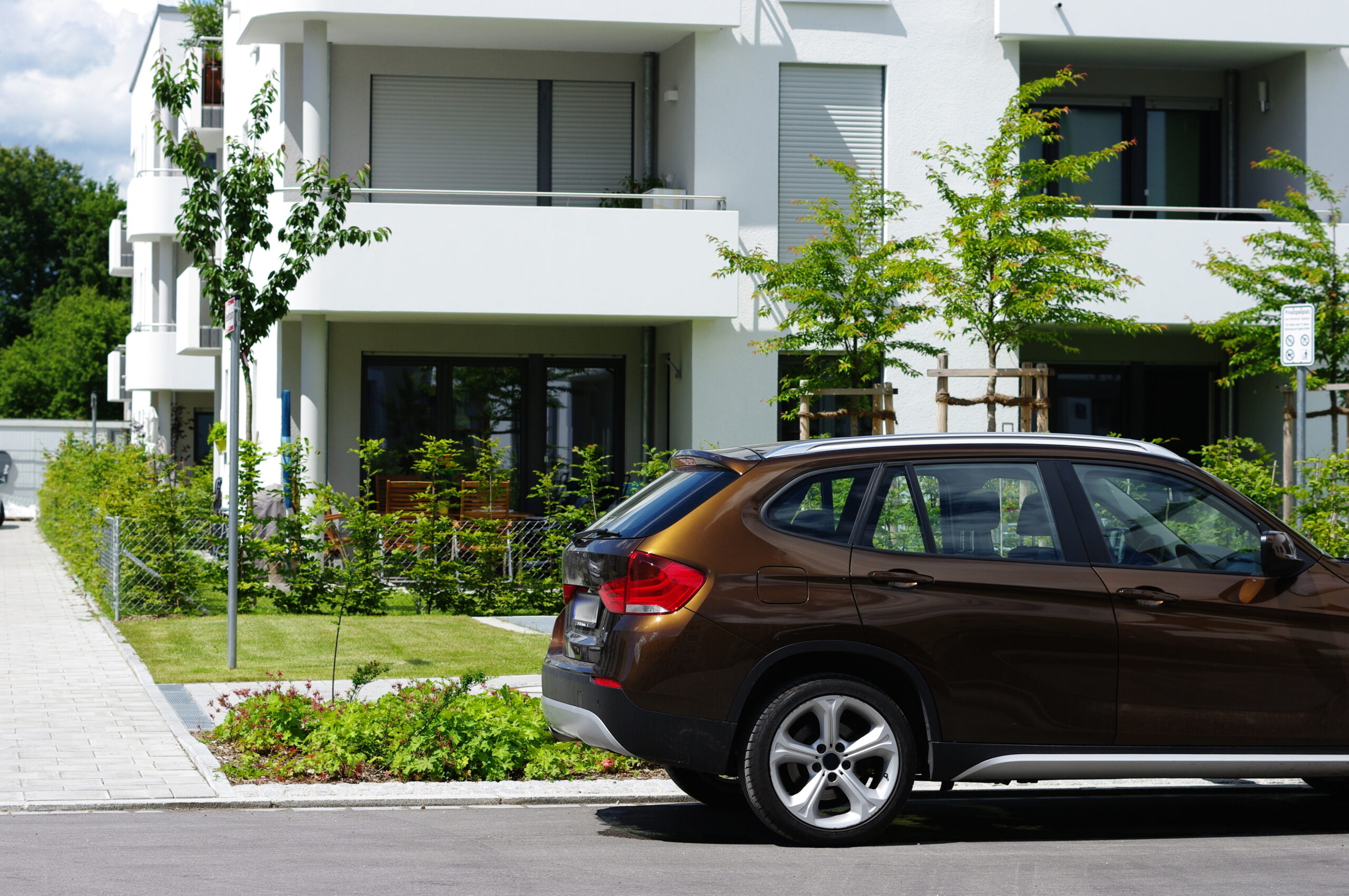 Auto parkt vor einem Mehrfamilienhaus in einem Neubaugebiet