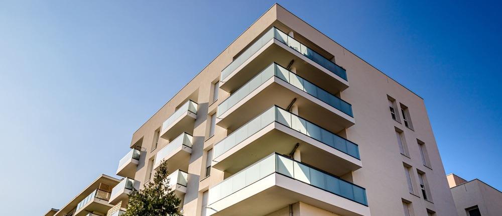Modernes Mehrfamilienhaus mit Glasbalkonen.
