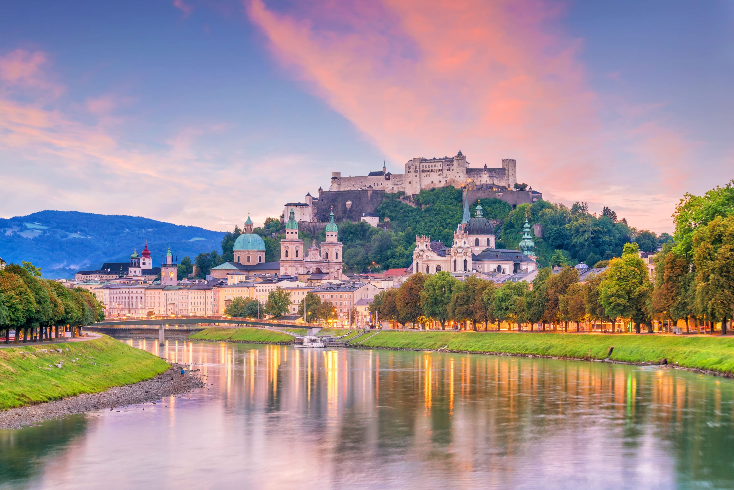 Abendliche Stadtansicht von Salzburg mit der Festung Hohensalzburg und dem Fluss Salzach.