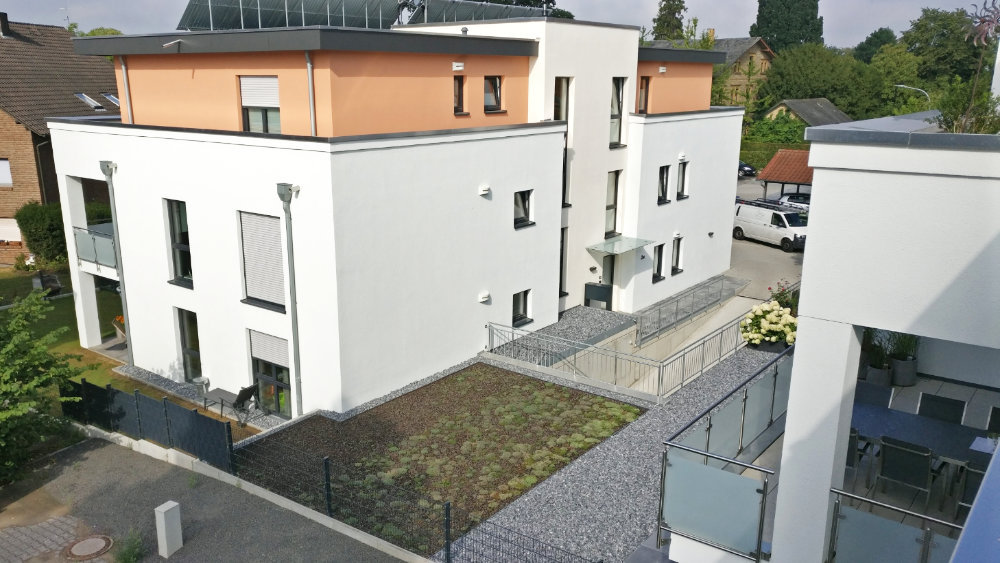Modernes Mehrfamilienhaus mit Flachdach und hellem Putz, Neubauprojekt.
