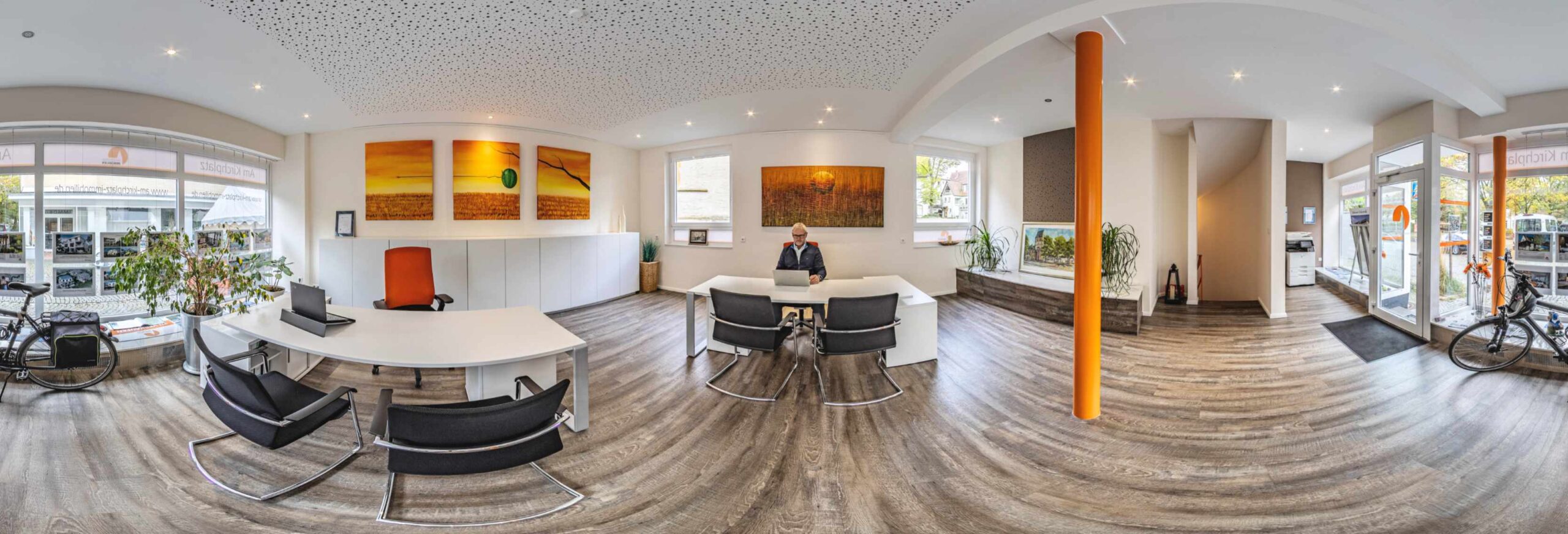 Geschäftsführer oder Makler arbeitet in hellem Büro mit orangefarbenem Akzent.