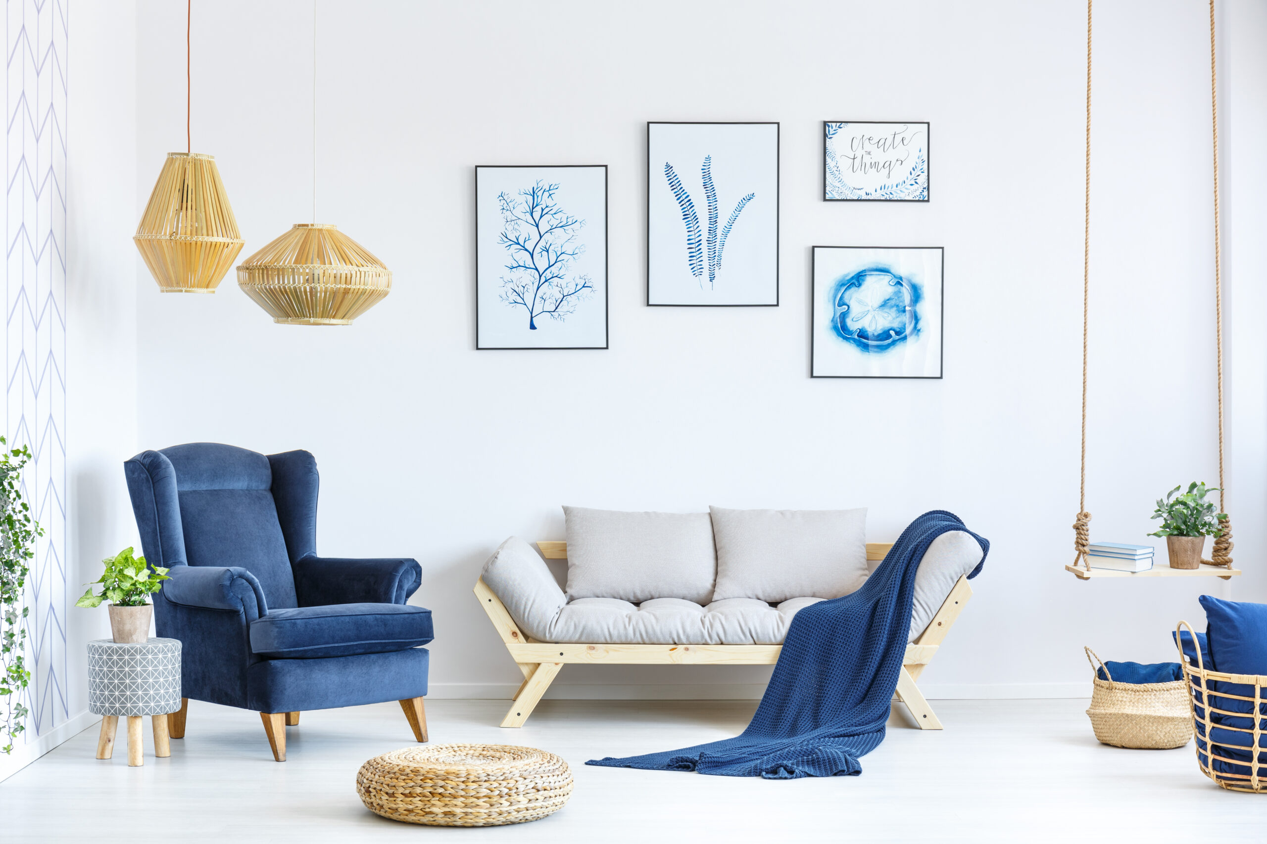 Helles und modern eingerichtetes Wohnzimmer mit blauem Sessel und Rattan-Lampen.