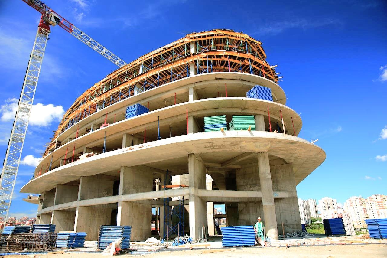 Immobilienprojekt: Großes, modernes Gebäude im Rohbau mit Baukran.