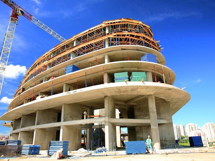 Immobilienprojekt: Großes, modernes Gebäude im Rohbau mit Baukran.