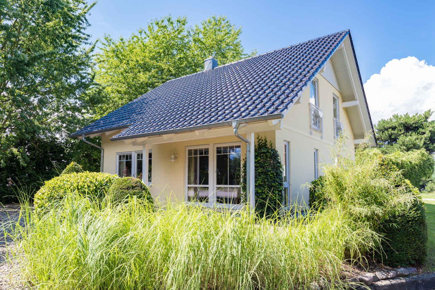 Modernes gelbes Haus im Grünen an einem sonnigen Tag.