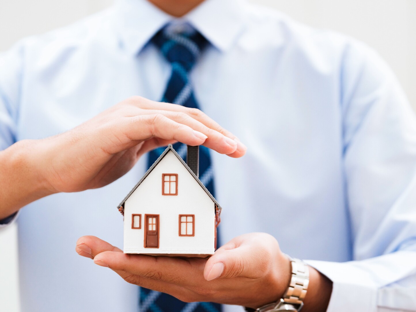 Mann mit einem Miniaturhaus in der Hand