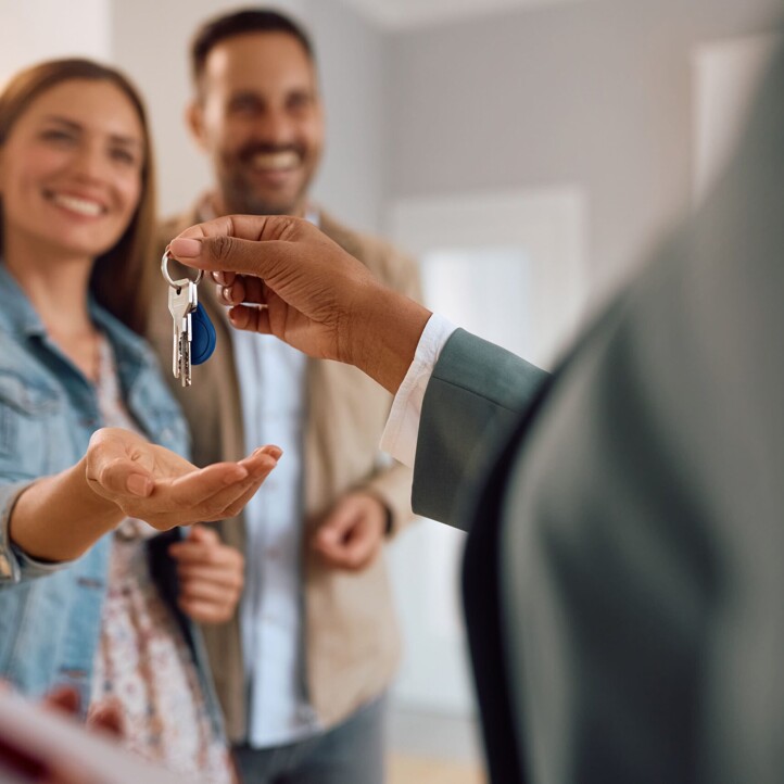 Glückliches Paar bekommt Immobilienschlüssel überreicht