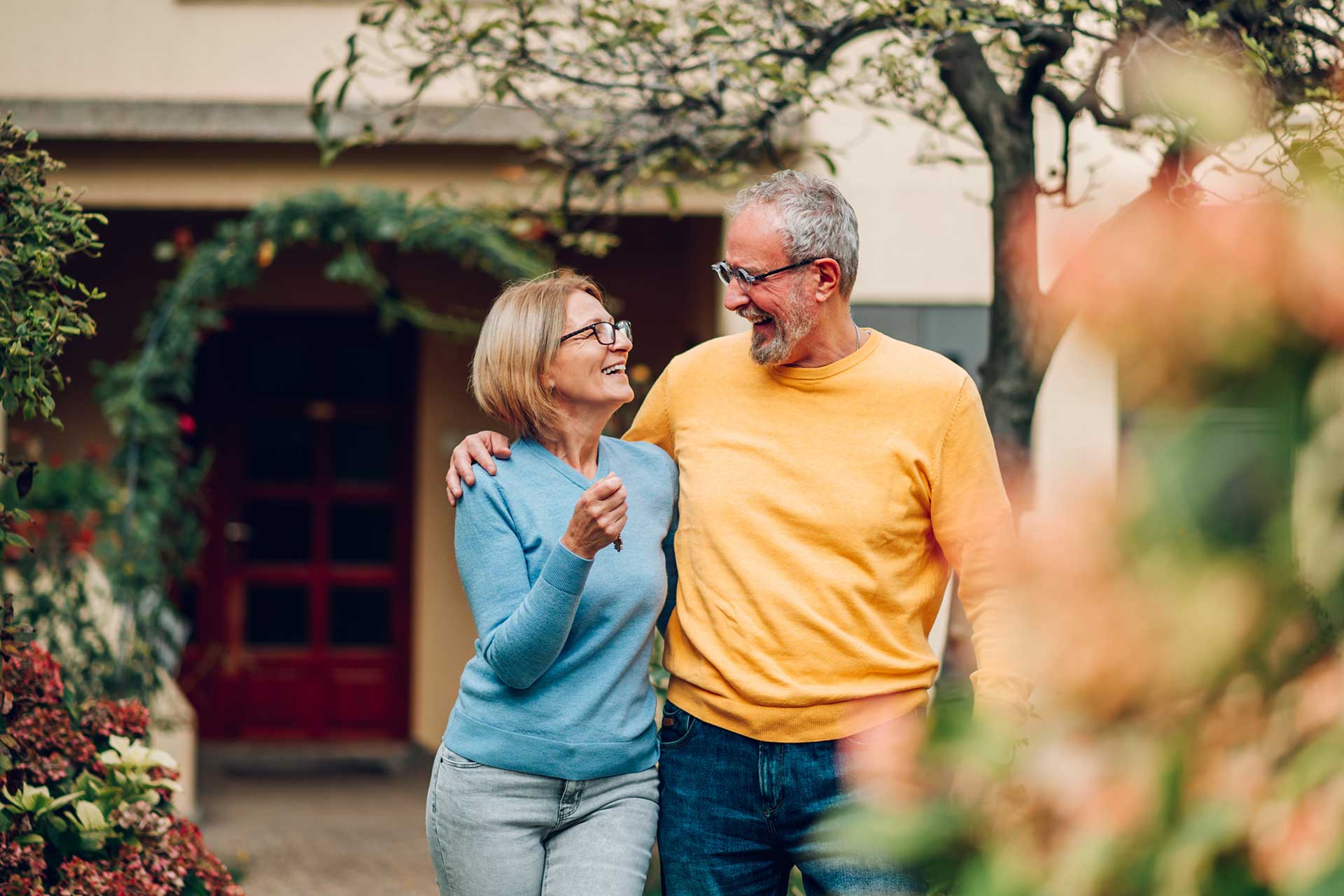 Älteres Paar mit Hausschlüssel in der Einfahrt: Verkauf in der Zinswende