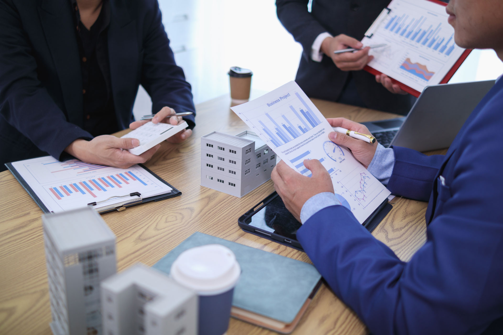 Immobilienmakler mit Unterlagen und Modellhäusern am Tisch: Immobiliengutachten