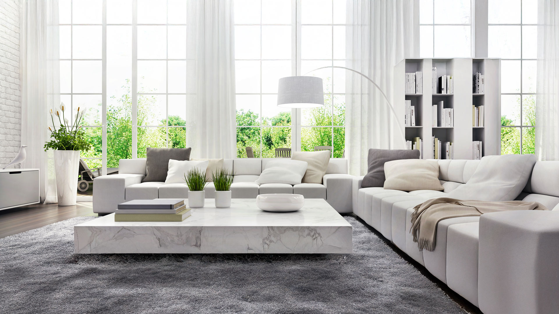 Modernes Wohnzimmer mit großen Fenstern, weißen Sofas, Pflanzen.