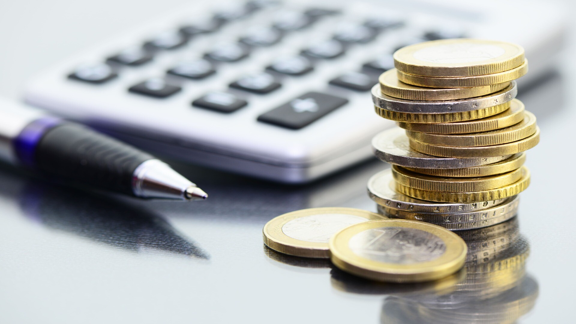 Ein Stapel Euro Münzen vor einem Taschenrechner