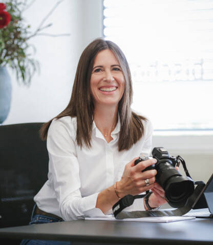 Sabine Bischof mit professioneller Kamera am Schreibtisch