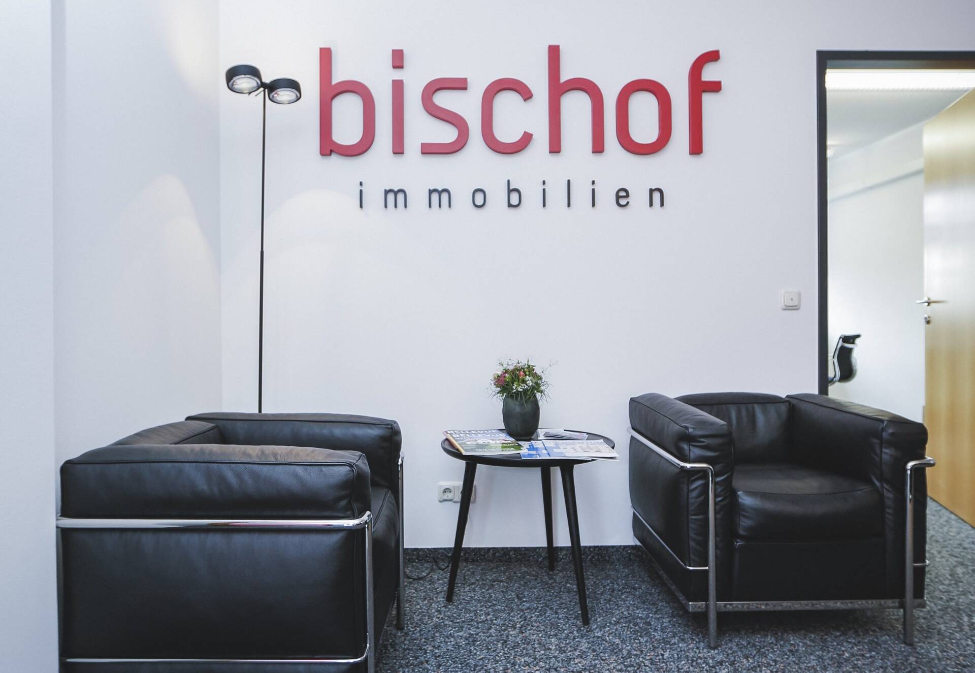 Warteraum im Büro von Bischof Immobilien mit Logo an der Wand