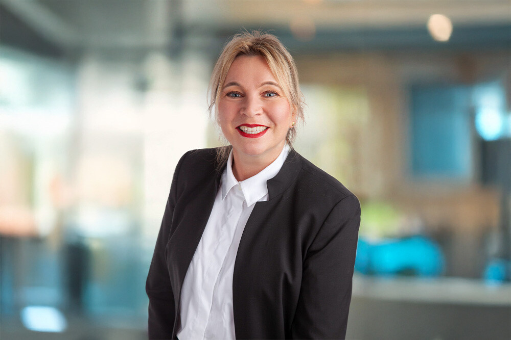 Frau im schwarzen Blazer und weißem Hemd im modernen Büro.
