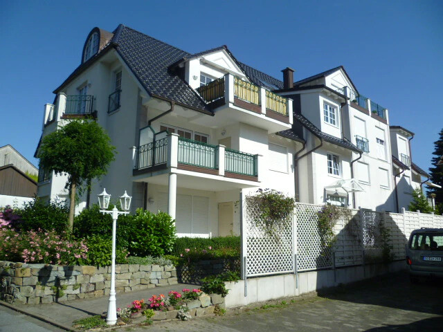 Ein Mehrfamilienhaus mit Vorgarten und Balkon