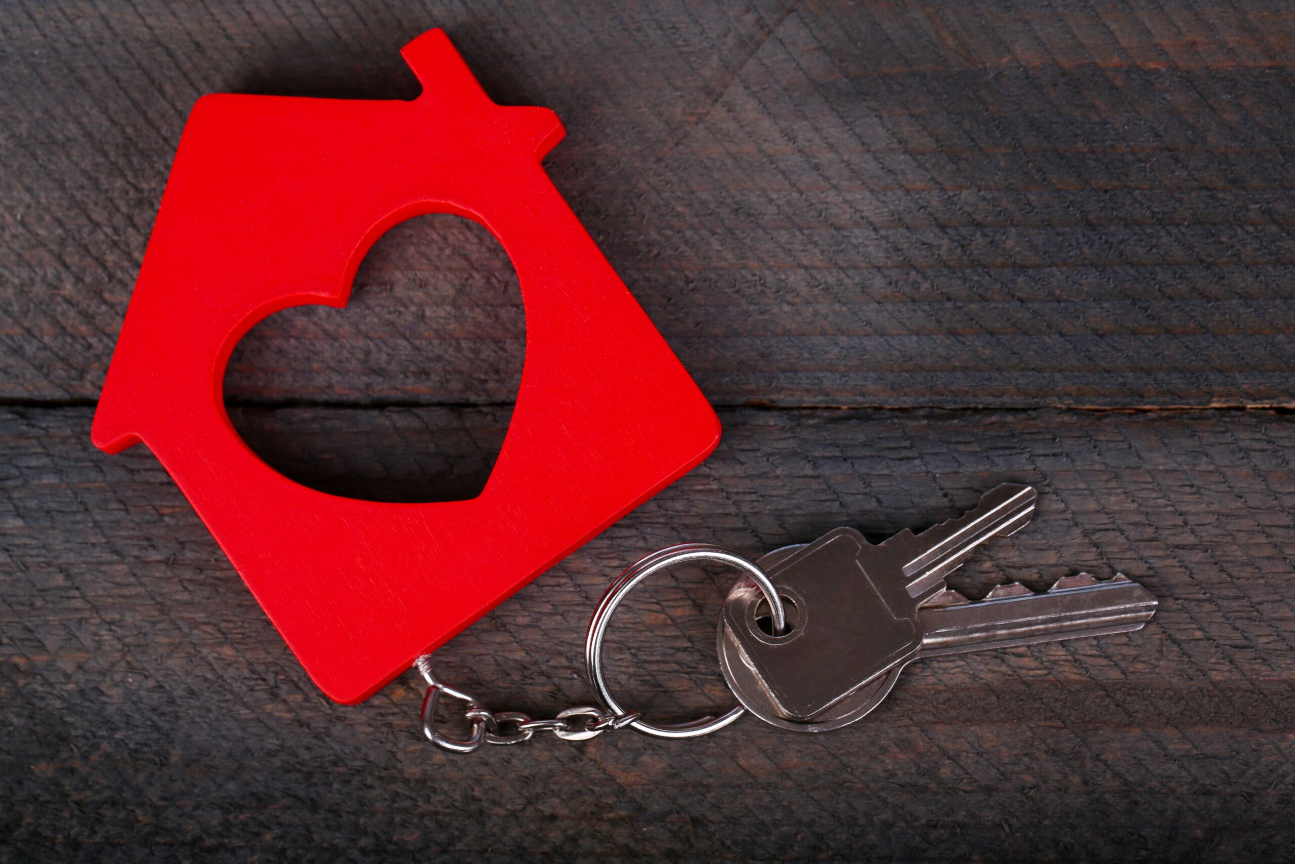 Ein Schlüssel mit einem Schlüsselanhänger, der ein rotes Haus mit Herz darstellt