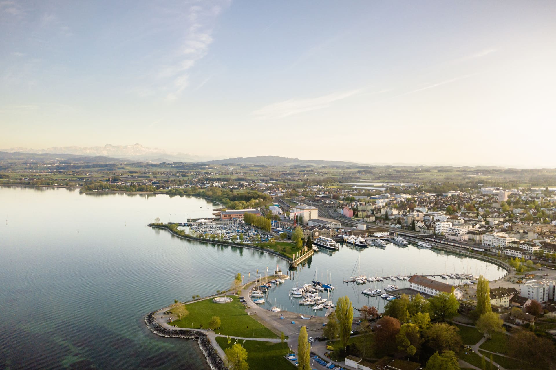 Fährhafen von Romanshorn am Bodensee bei Sonnenuntergang mit Booten und Hafenanlage.