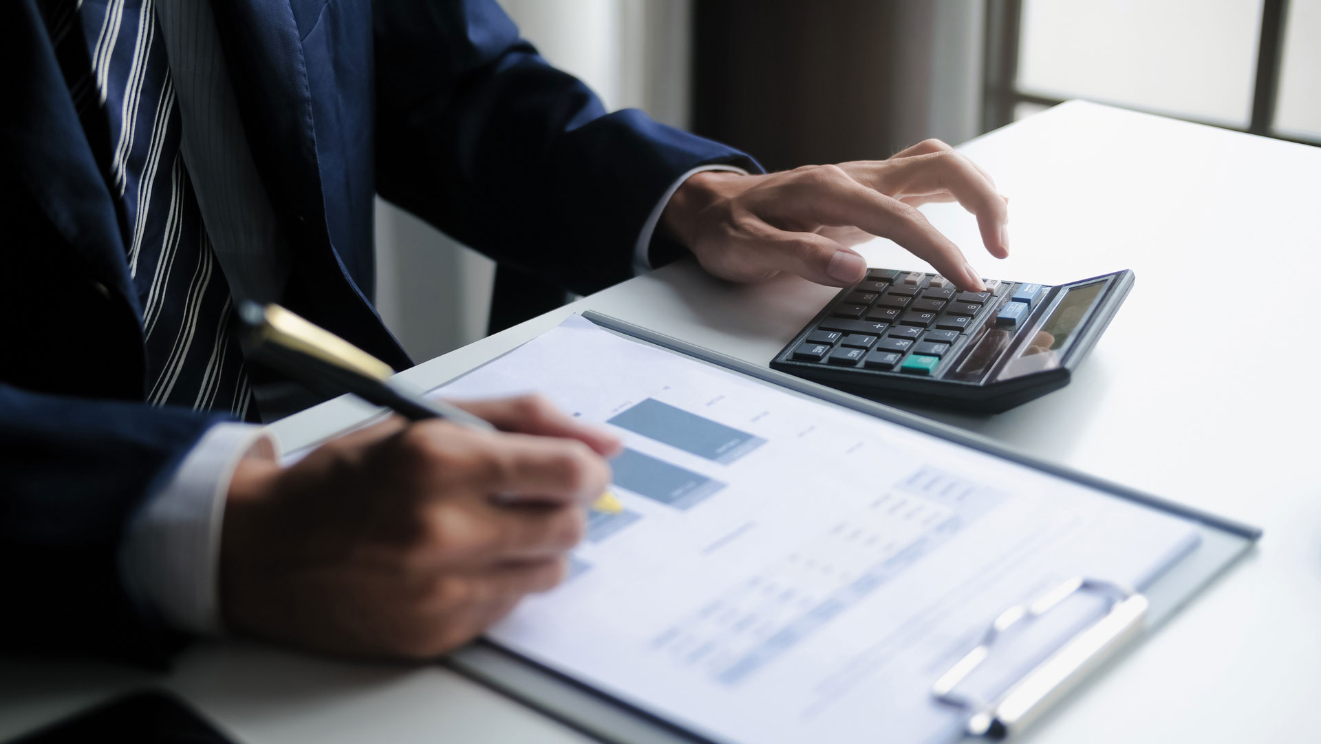 Mann arbeitet an Unterlagen und Taschenrechner